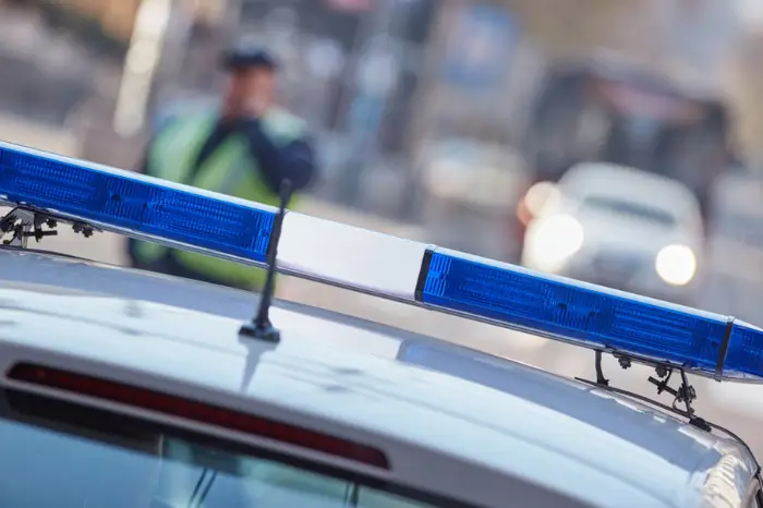 Police car with blue lights on the crime scene in traffic / urban environment.