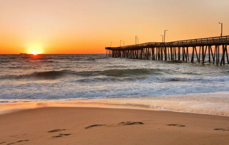 Fishing Pier at Sunrise at Virginia Beach, Virginia, USA. Virginia Beach, a coastal city in southeastern Virginia, lies where the Chesapeake Bay meets the Atlantic Ocean.