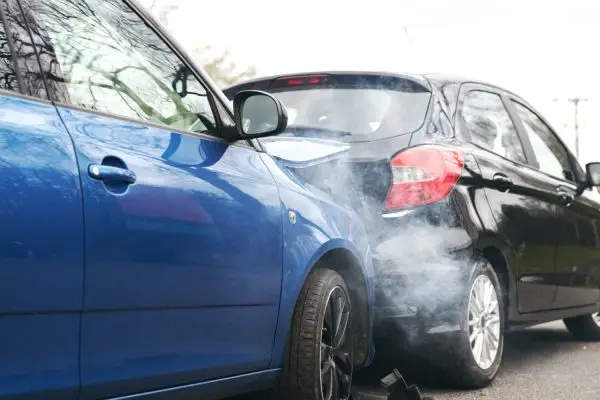 Two cars involved in traffic accident on side of the road with damage to bonnet and fender