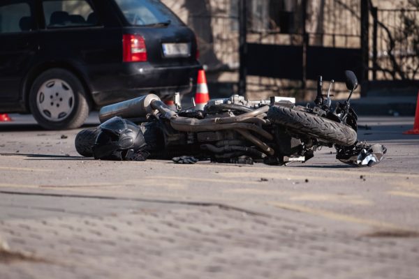 Accident with motorcycle at a crossroads. A motorcyclist's helmet lies next to a broken bike. Oil leaked from the bike. The motorcyclist was taken