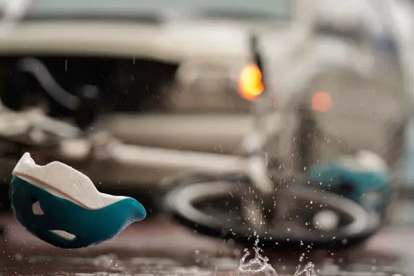 Blurred image of a traffic accident, helmet and bicycle after a car crashes into a cyclist on the road during heavy rain, spot focus.