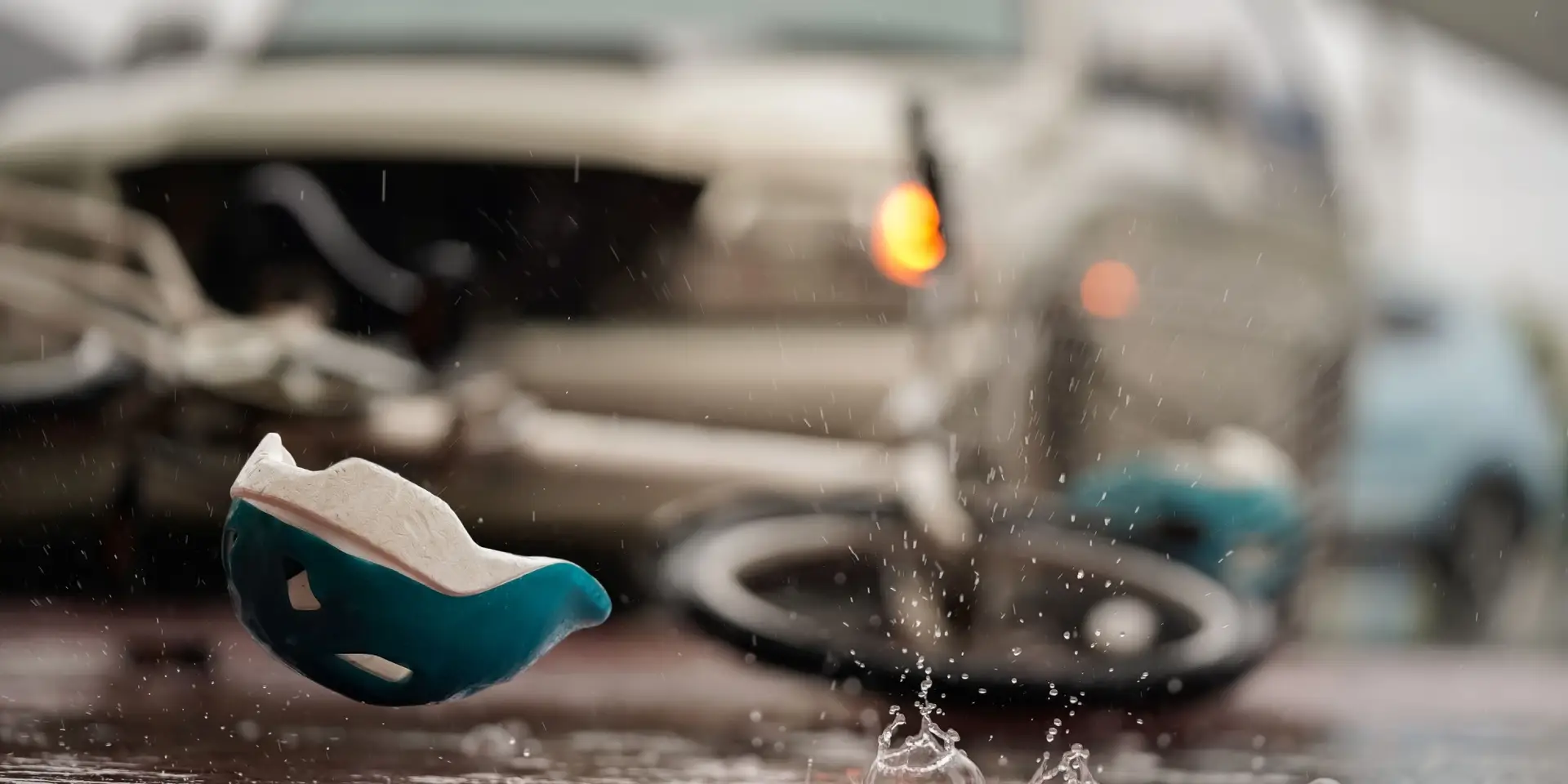 Blurred image of a traffic accident, helmet and bicycle after a car crashes into a cyclist on the road during heavy rain, spot focus.