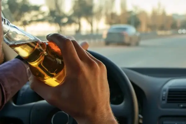 A man drinking alcohol while driving. Drunk driving concept.