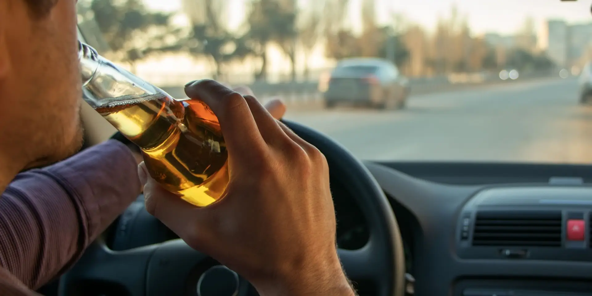 A man drinking alcohol while driving. Drunk driving concept.