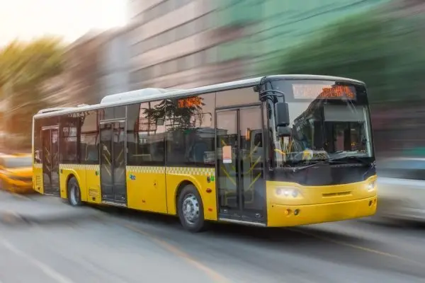 City yellow bus rush motion blur effect through the streets of the city in the evening at sunset peak hour